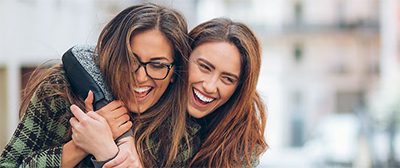women smiling and one of them are wearing glasses